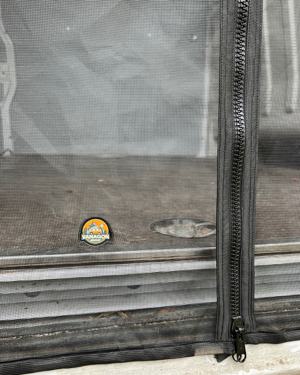 Close-up of a mesh screen with a zipper, featuring a logo on a wooden surface.