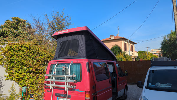 Red ford nugget van with a black rooftop tent replacement freshly installed.