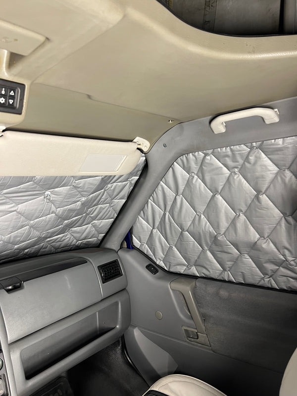 Car interior with quilted gray insulation panels on the doors and backrest.