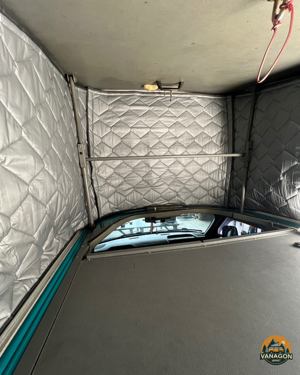 Interior of a van with quilted walls and a window, featuring the Vanagon brand.